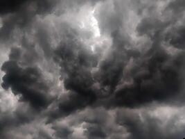 Dark, looming storm clouds dominate the sky, creating a moody, dramatic atmosphere. The overcast sky hints at an impending rainstorm, with thick clouds rolling in and covering the horizon. photo