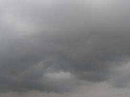 Dark, looming storm clouds dominate the sky, creating a moody, dramatic atmosphere. The overcast sky hints at an impending rainstorm, with thick clouds rolling in and covering the horizon. photo