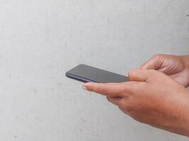 Close-up of hands holding a smartphone, fingers scrolling on the screen. Minimalist background, focus on technology and human interaction. Perfect for tech, digital, and lifestyle themes. photo