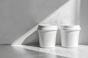 Two white coffee cups on a table with shadows photo