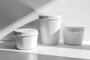 Three white containers with lids sit on a table photo