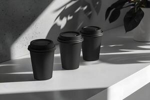 Three black coffee cups sit on a white counter photo