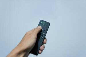 a hand pressing a button of a remote control photo