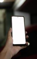 A hand holding a smartphone with a blank white screen photo