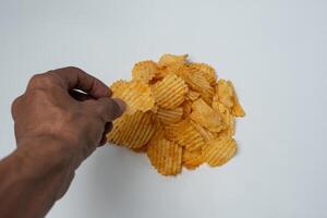 A hand reaching for a chip from a pile of potato chips photo