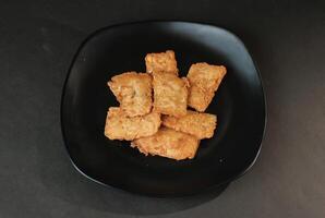 crispy flour fried tempeh which is served on a plate. photo