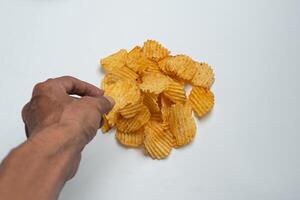 A hand reaching for a potato chip photo