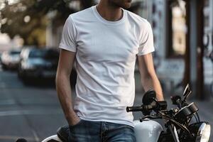 Man in white t-shirt and jeans standing on a motorbike. photo