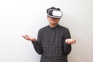 Portrait of Asian man in black plaid shirt using Virtual Reality VR glasses and protecting himself by spreading his arms from something big falling from above. Isolated image on white background photo