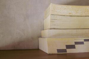 Stack of yellowish and vintage books on floating wooden bookshelf. Education and knowledge concept. Pile of books to read photo