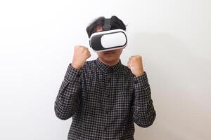 Portrait of Asian man in black plaid shirt using Virtual Reality VR glasses and trying to punch and fight something or his enemy game in front of him. Isolated image on white background photo