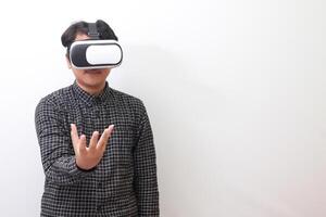 Portrait of Asian man in black plaid shirt using Virtual Reality VR glasses and trying to hold something in front of him. Isolated image on white background photo