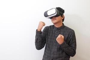 Portrait of Asian man in black plaid shirt using Virtual Reality VR glasses and trying to punch and fight something or his enemy game in front of him. Isolated image on white background photo