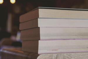 Stack of books on wooden desk in the library room background. Education and knowledge concept. Pile of books to read. photo