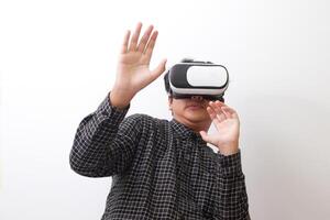 Portrait of Asian man in black plaid shirt using Virtual Reality VR glasses and protecting himself by spreading his arms from something big falling from above. Isolated image on white background photo