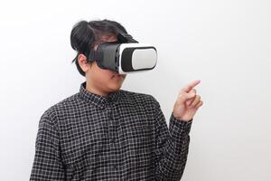 Portrait of Asian man in black plaid shirt using Virtual Reality VR glasses and trying to touch something in front of him. Isolated image on white background photo