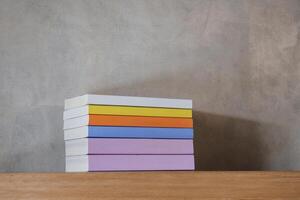 Stack of colorful books on floating wooden bookshelf. Education and knowledge concept. Pile of books to read. House interior decoration photo
