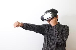 Portrait of Asian man in black plaid shirt using Virtual Reality VR glasses and trying to punch and fight something or his enemy game in front of him. Isolated image on white background photo