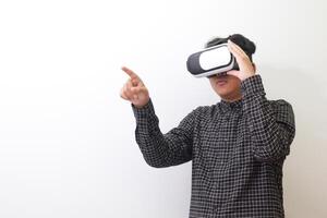 Portrait of Asian man in black plaid shirt using Virtual Reality VR glasses and trying to touch something in front of him. Isolated image on white background photo