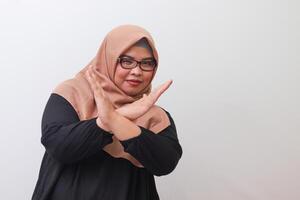 Portrait of serious Asian woman with hijab, showing X sign of hands for refusing an invitation from someone. Isolated image on white background photo
