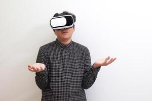Portrait of Asian man in black plaid shirt using Virtual Reality VR glasses and protecting himself by spreading his arms from something big falling from above. Isolated image on white background photo