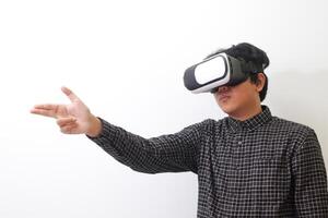 Portrait of Asian man in black plaid shirt using Virtual Reality VR glasses and greet his friend inside the game with opened palm. Isolated image on white background photo