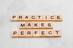 Top view of Practice Makes Perfect words on wooden cube letter block on white background. Business concept photo