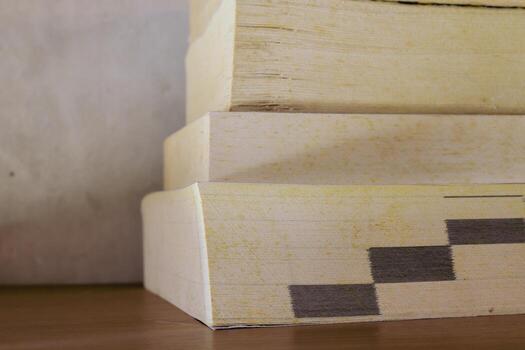 Stack of yellowish and vintage books on floating wooden bookshelf. Education and knowledge concept. Pile of books to read photo