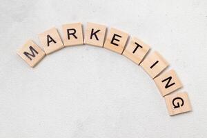 Top view of Marketing word on wooden cube letter block on white background. Business concept photo