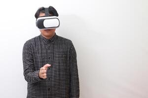 Portrait of Asian man in black plaid shirt using Virtual Reality VR glasses reaching out for a handshake and greet someone or his friend inside the game. Isolated image on white background photo