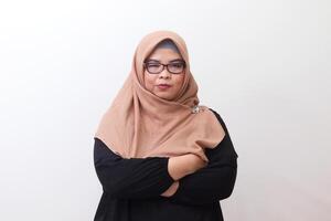 Portrait of annoyed Asian woman with hijab keeping arms crossed and looking at camera with skeptical and distrustful look. Isolated image on white background photo