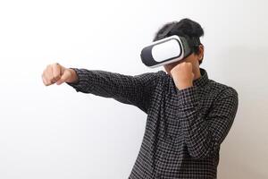 Portrait of Asian man in black plaid shirt using Virtual Reality VR glasses and trying to punch and fight something or his enemy game in front of him. Isolated image on white background photo