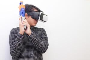 Portrait of Asian man in black plaid shirt using Virtual Reality VR glasses holding a gun weapon console. Isolated image on white background photo