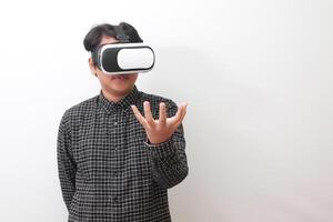 Portrait of Asian man in black plaid shirt using Virtual Reality VR glasses and trying to hold something in front of him. Isolated image on white background photo