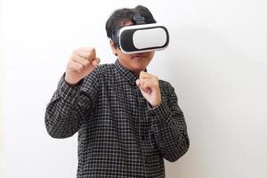 Portrait of Asian man in black plaid shirt using Virtual Reality VR glasses and trying to punch and fight something or his enemy game in front of him. Isolated image on white background photo