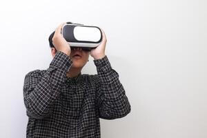 Portrait of Asian man in black plaid shirt using Virtual Reality VR glasses and looking up. Isolated image on white background photo