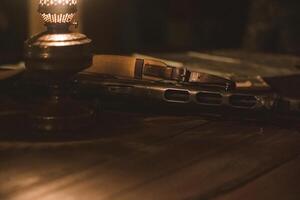An old Soviet rifle lies on a table next to a kerosene lamp in the semi-darkness photo