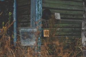 A bucket hangs on a chain against the background of an old, rustic house photo