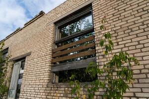 The window is boarded up. The window of an old, abandoned, brick store building photo