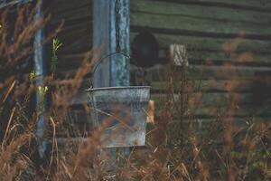 A bucket hangs on a chain against the background of an old, rustic house photo