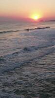 A sunset over the ocean with waves and a beach video