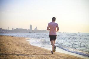 Man running on the beach at sunset photo