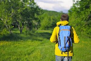 Man with backpack hiking in forest photo
