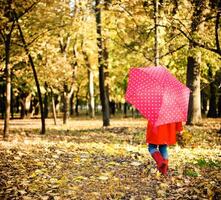 Little girl with polka dots umbrella walking through alley photo