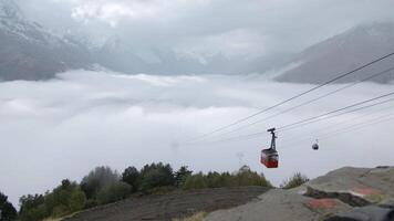 Mountain lift with mountain view with clouds. Creative. Cable car with moving funiculars in snowy mountains. Beautiful view from cable car on background of clouds and snowy mountain peaks video