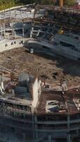 Top view of construction of large stadium in city. Stock footage. Process of building stadium on site with cranes in modern city. Construction of stadium with cranes on sunny day video