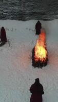 Group of hooded by the fire in the mountains. Footage. The scene of the sacrifice in the mountains in winter. Religious ritual of sacrifice of addition video