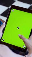 Close-up of man holding tablet and touching green screen. Stock fooatge. Young freelancer uses tablet to work or create projects. Tablet with green screen to insert video