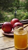 Apples red whole and sliced with a jar of honey on the traditional Jewish holiday of Rosh Hashana on a wooden table by the window on a sunny day. Close-up, vertical video
