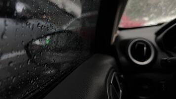 Inside a car during rain, droplets cascade down the window, creating a tranquil atmosphere. Raindrops blend with reflections, enhancing the cozy drive. video